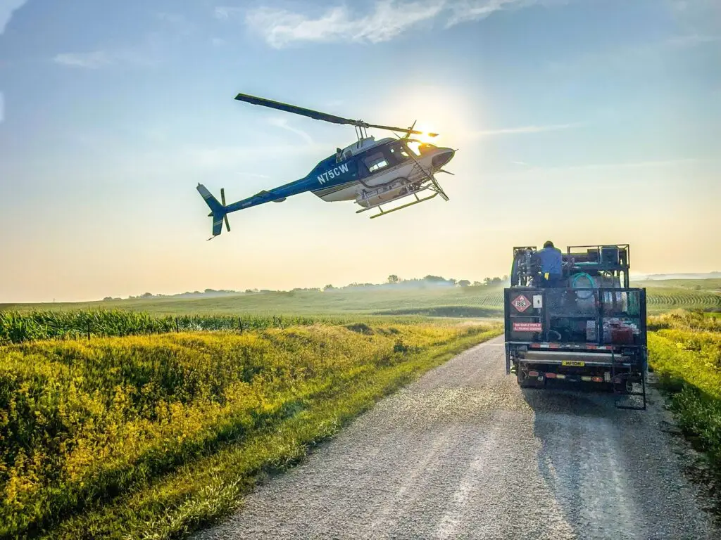 Helicopter performing aerial spraying over crops for precise pesticide application. LiDAR